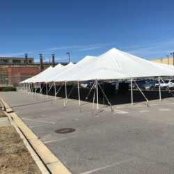 Large white canopy tents set up in a parking lot under a clear blue sky.