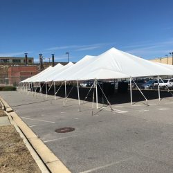 Large white canopy tents set up in a parking lot under a clear blue sky.