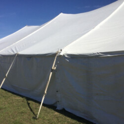 Large white event tent set up on grass under a clear blue sky.