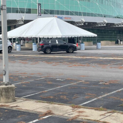 A black SUV parked near a large white tent outside PNC Arena in a mostly empty parking lot.